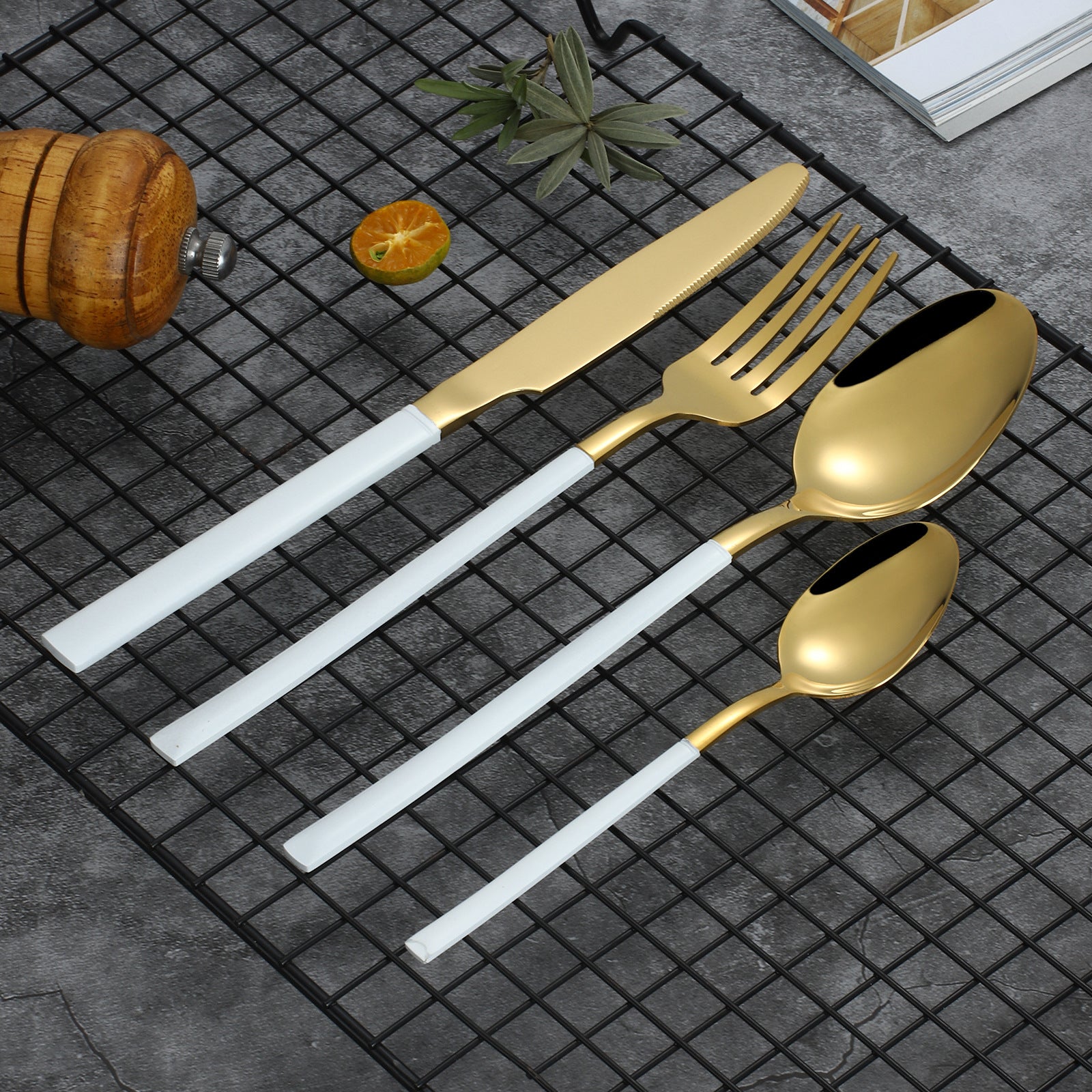 Set of gold cutlery with white handles on a dark textured surface.