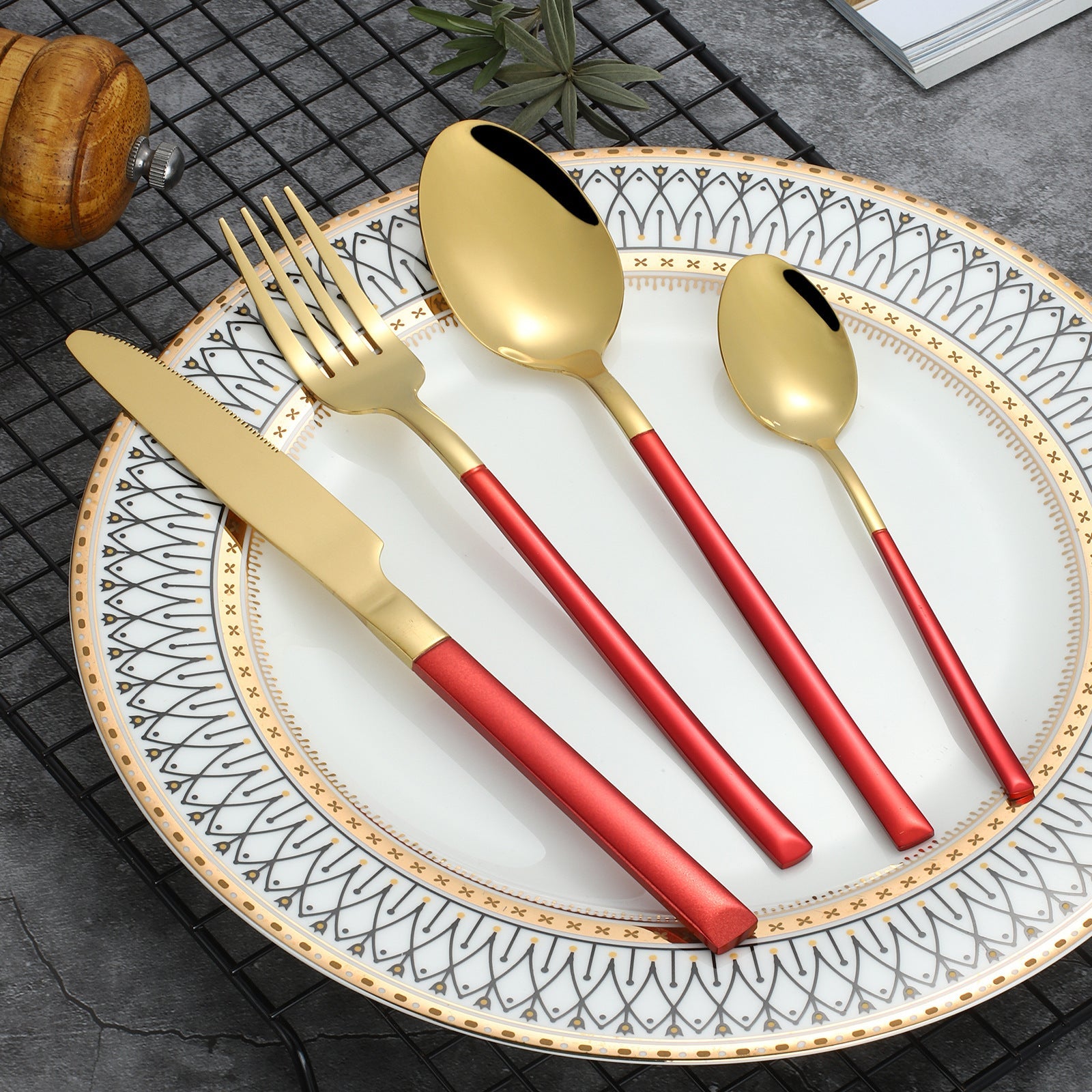 Gold and red cutlery set on a decorative plate with a textured surface.