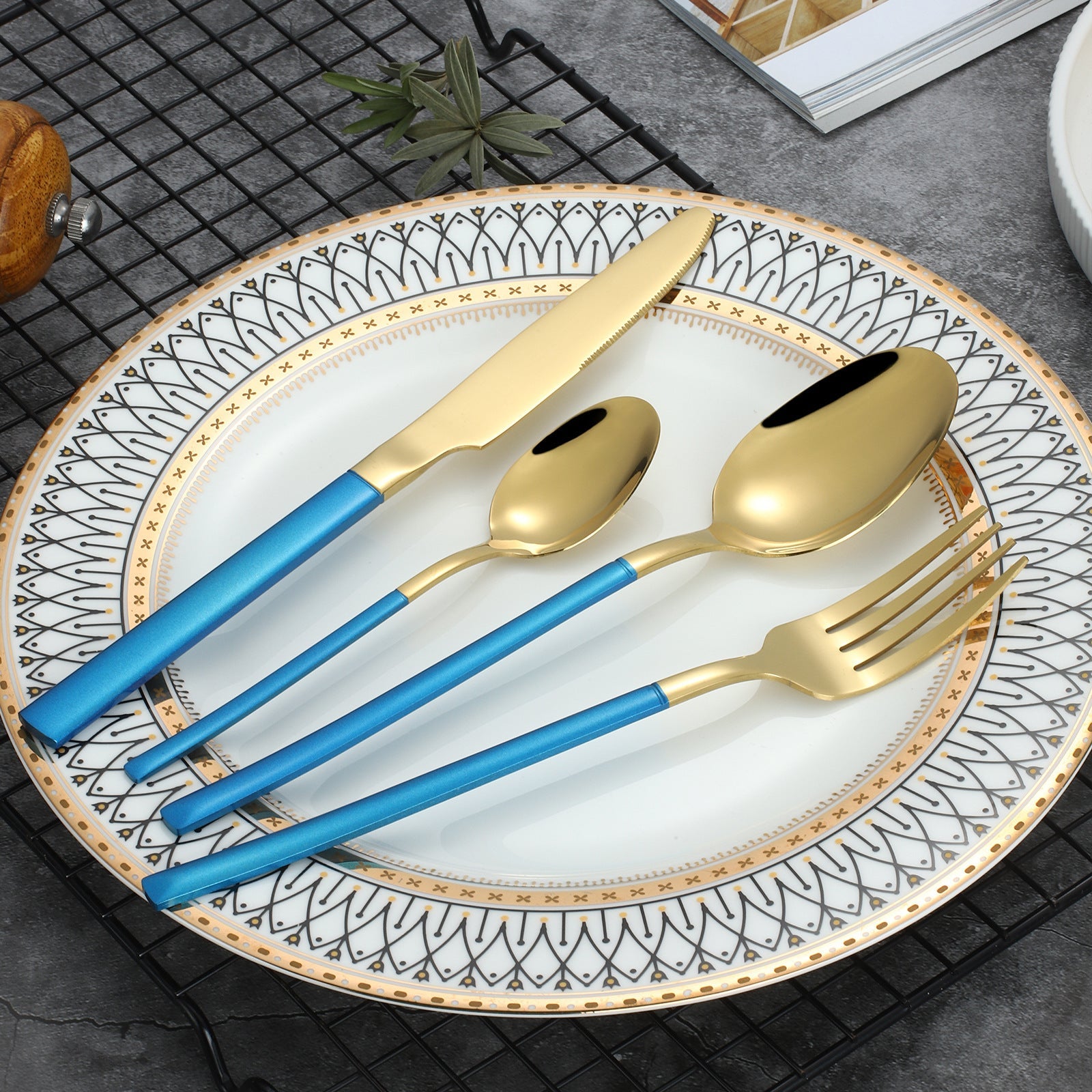 Gold and blue cutlery set on a decorative plate with a geometric pattern.