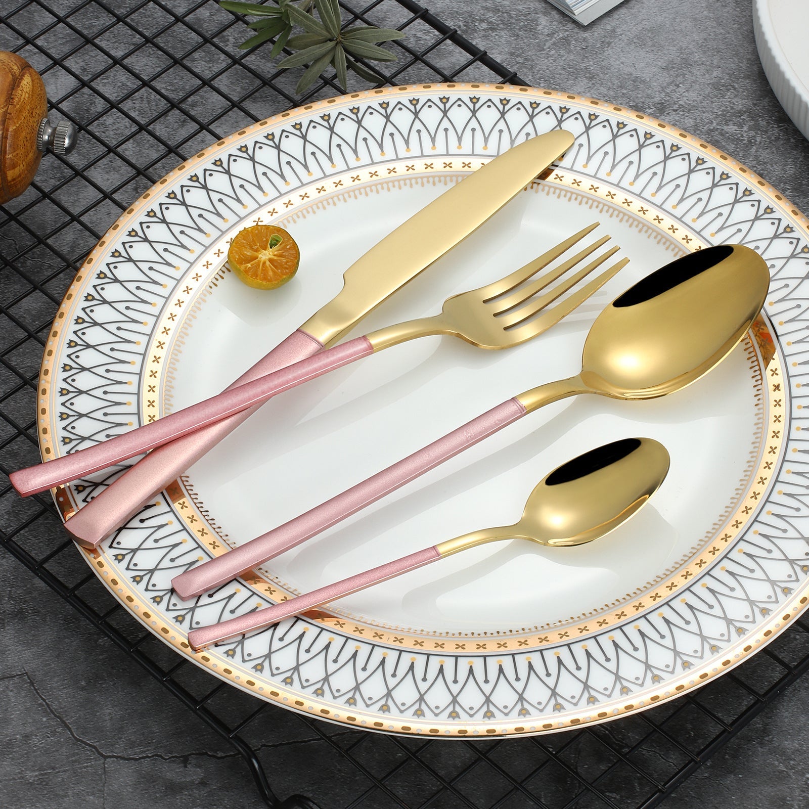 Set of pink-handled cutlery on a decorative plate with a geometric pattern.
