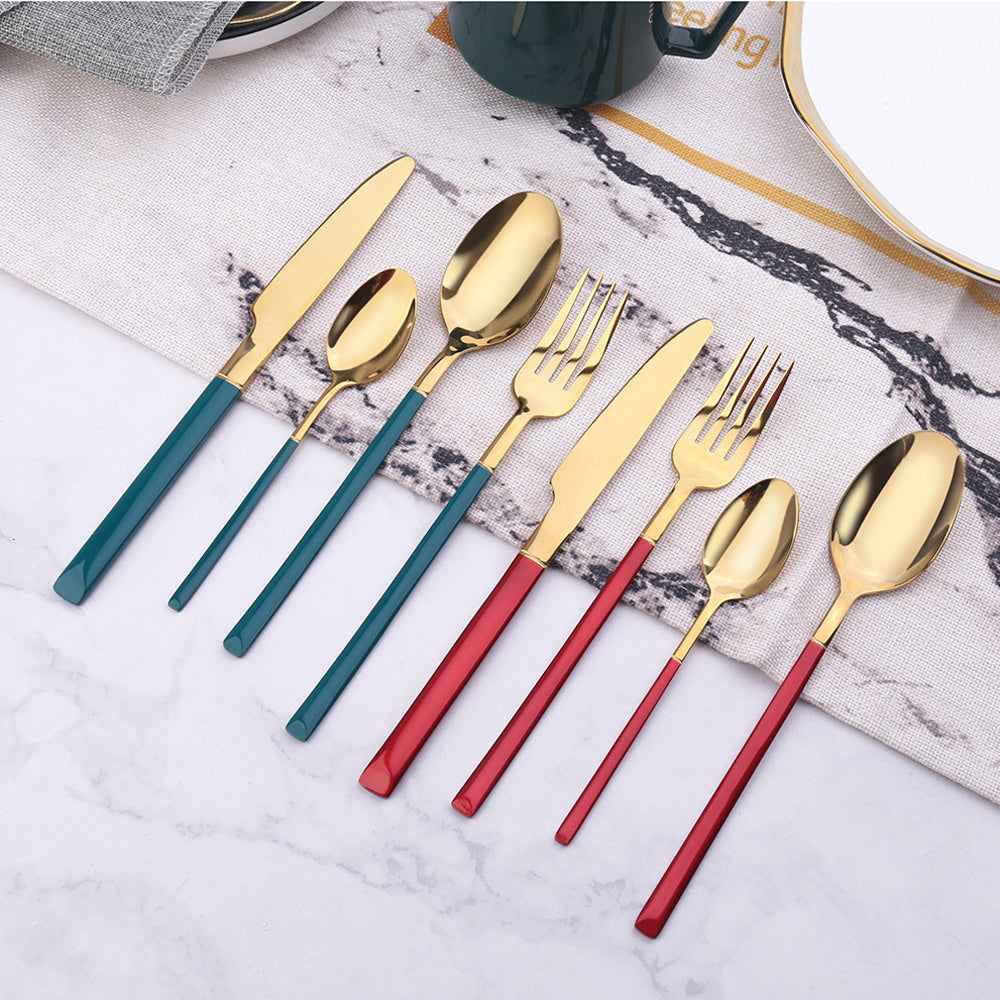Set of gold cutlery with blue and red handles on a marble surface