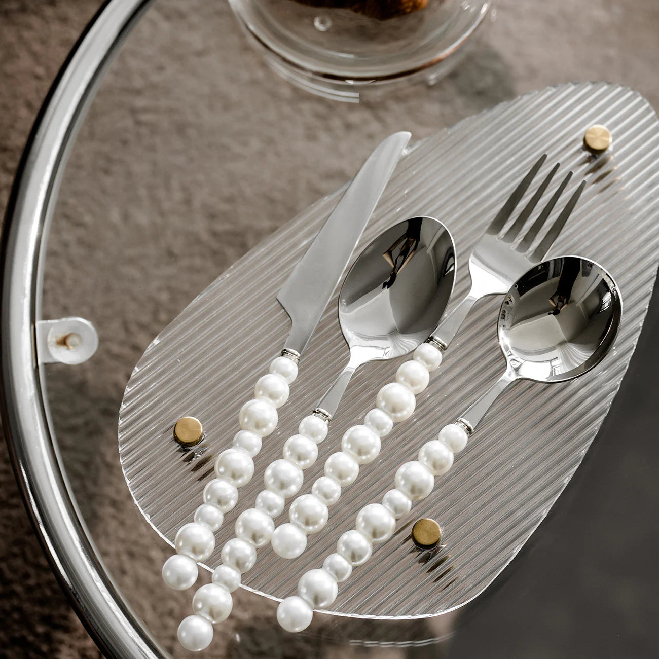 Silver cutlery set with pearl decorations on a textured surface