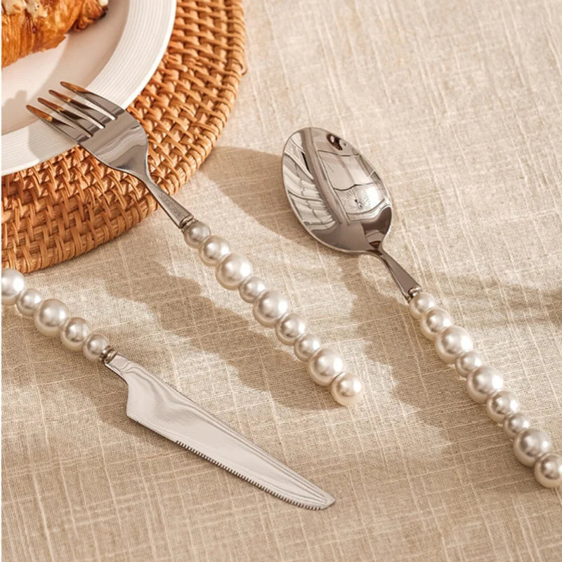 Silver cutlery set with pearl handles on a textured surface