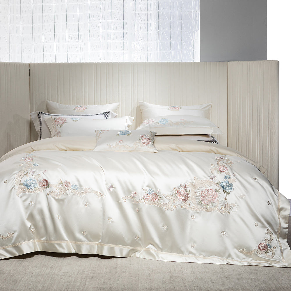 Floral embroidered bedding set on a bed with a neutral headboard.