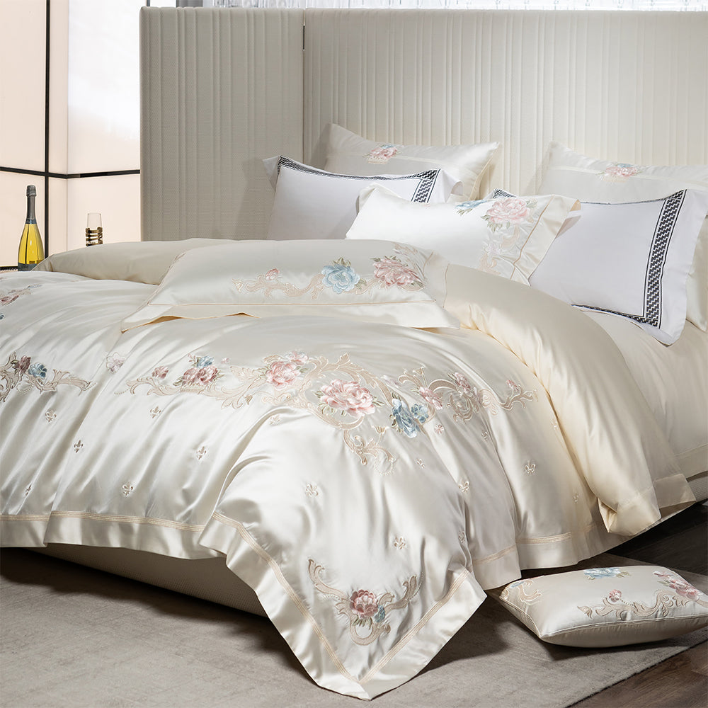 Floral embroidered bedding set on a bed with pillows in a bedroom setting.