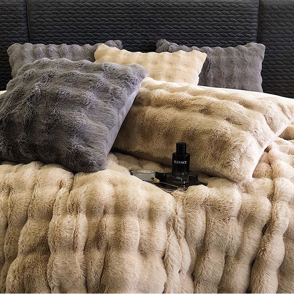 Beige faux rabbit fur bedding with gray and beige pillows on a dark textured headboard.