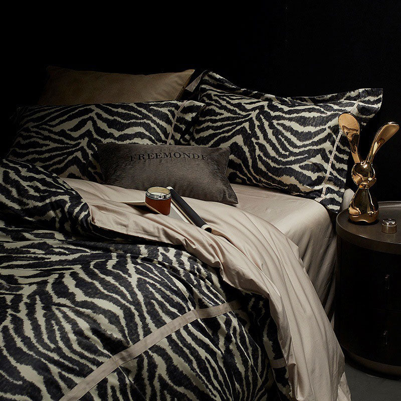 Bed with zebra print bedding and a nightstand with decorative items.