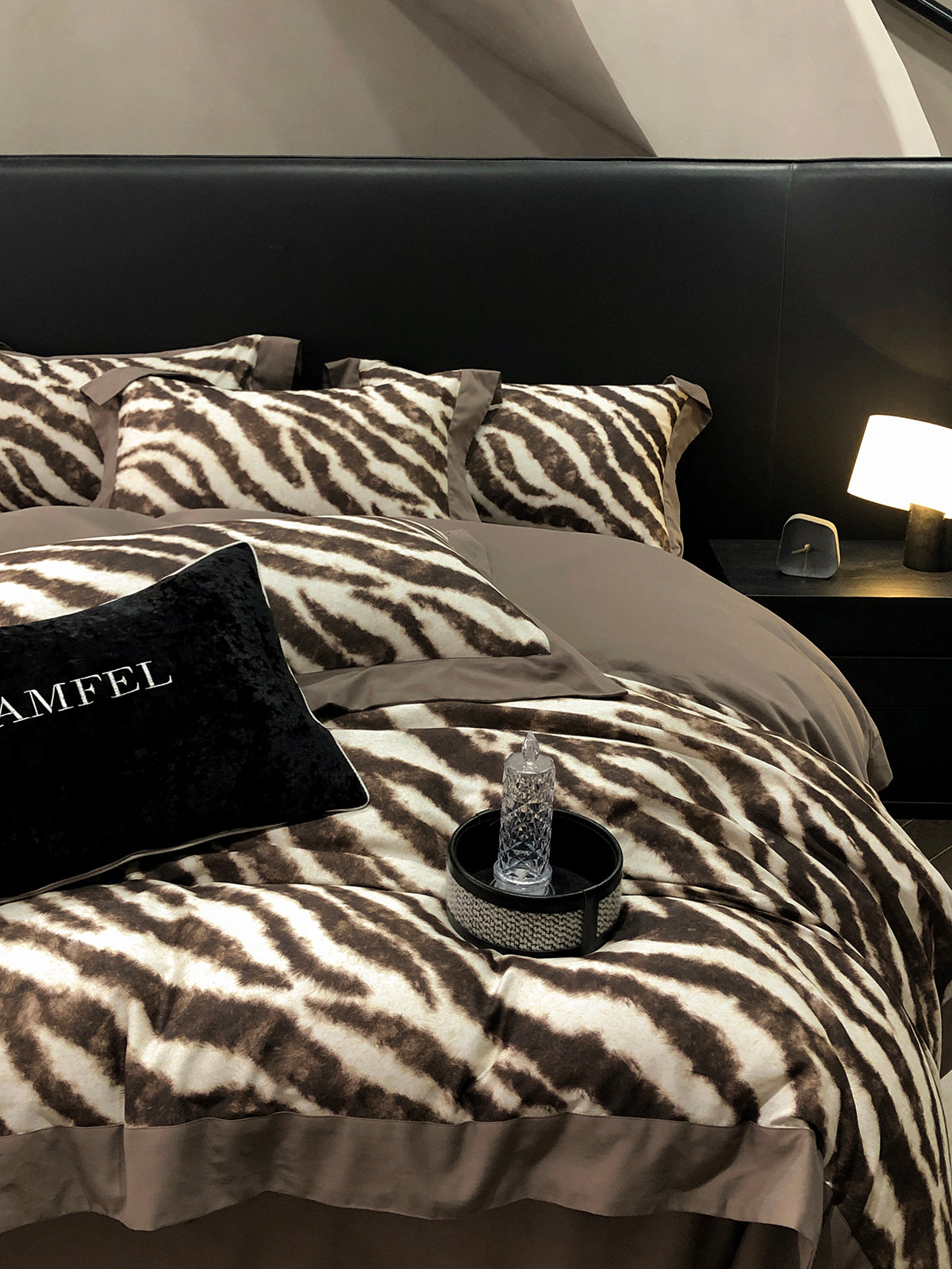 Bed with zebra print bedding and a black pillow with 'AMFEL' branding.