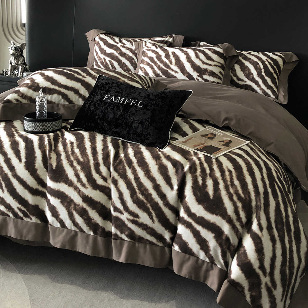 Bed with zebra print bedding and brown comforter, featuring a pillow with 'FAMEL' branding.