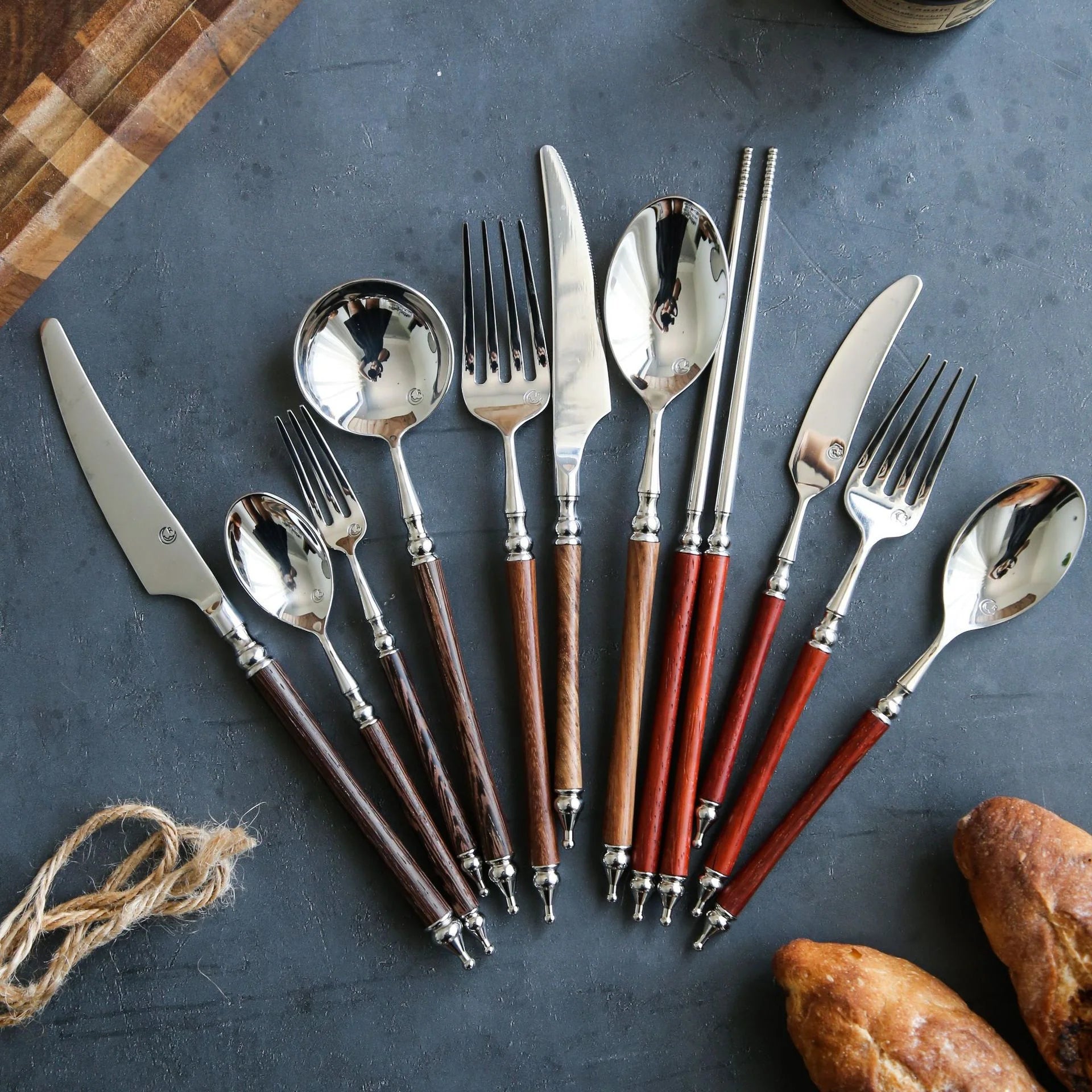 Set of silver cutlery with brown handles on a dark surface.