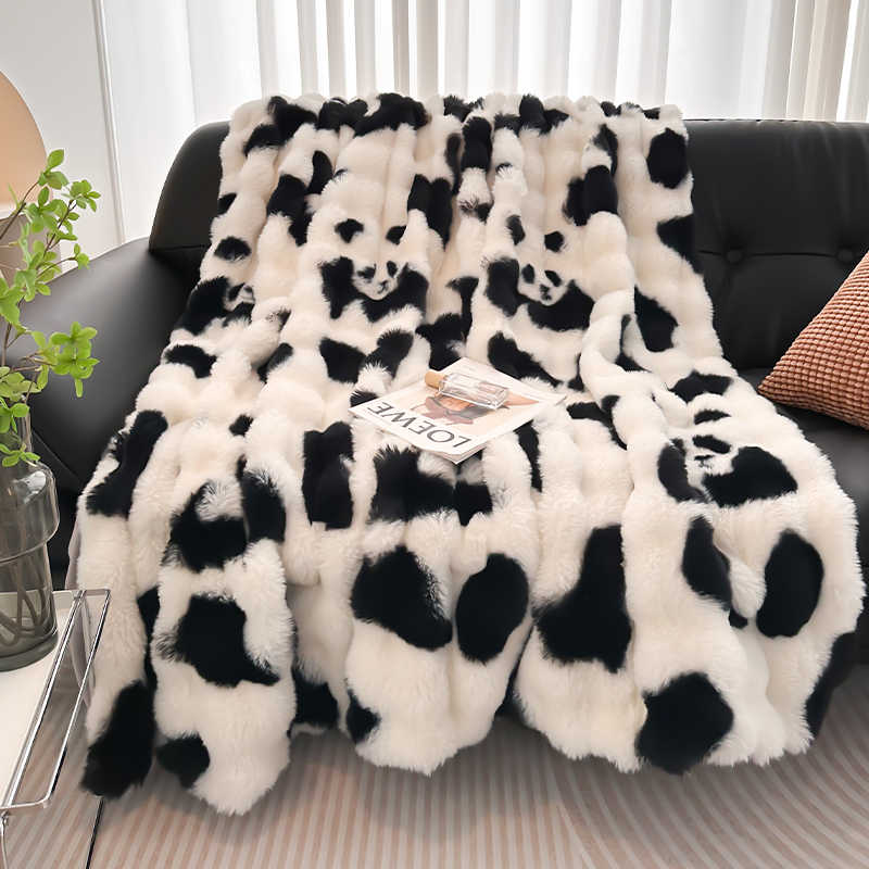 Black and white panda print blanket draped over a sofa with a magazine underneath.
