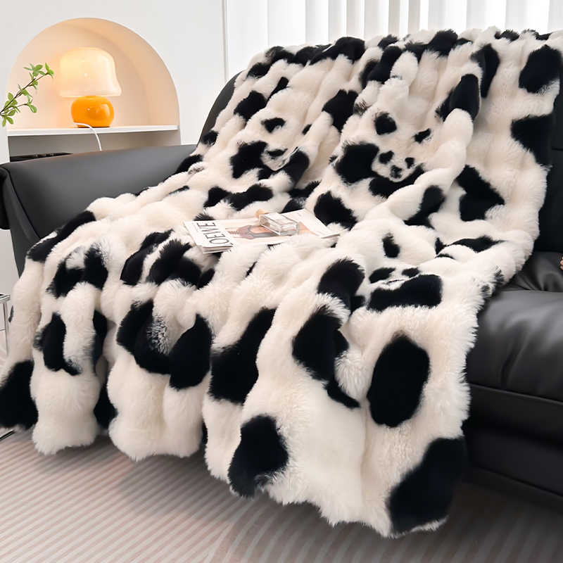 Black and white panda blanket draped over a black sofa in a living room setting.