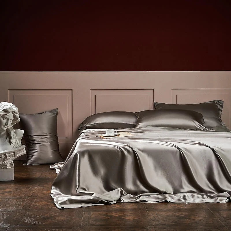 Gray satin bedding set on a bed with a dark wooden floor and wall.