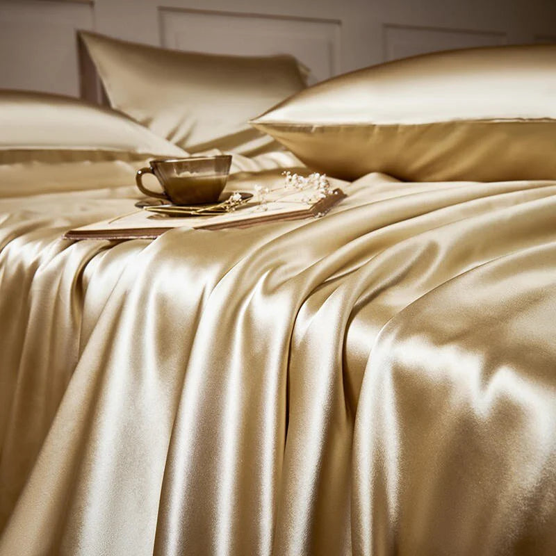 Gold satin bedding set with a cup and saucer on a bed.