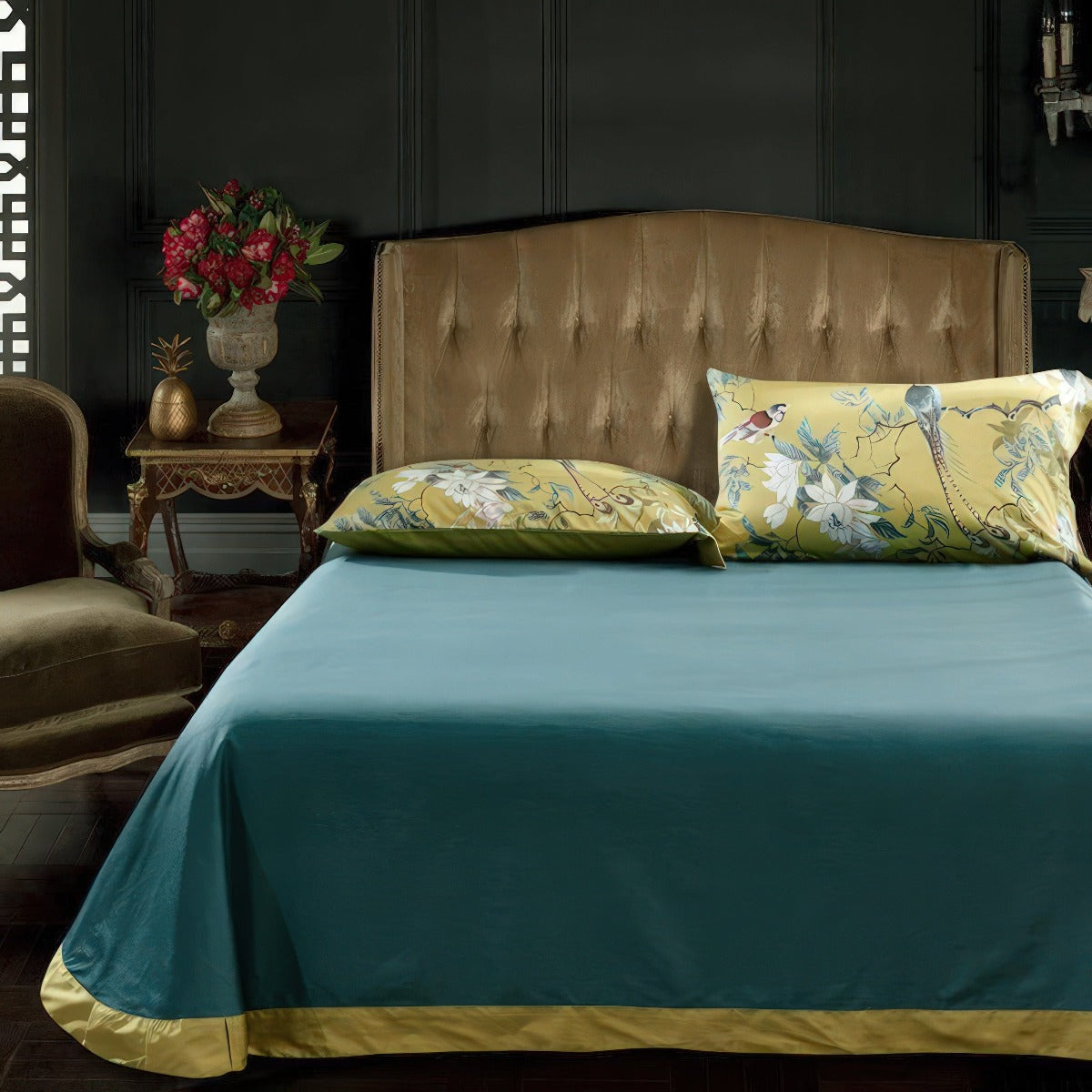 Bed with floral pillows and teal bedding in a darkly decorated room.