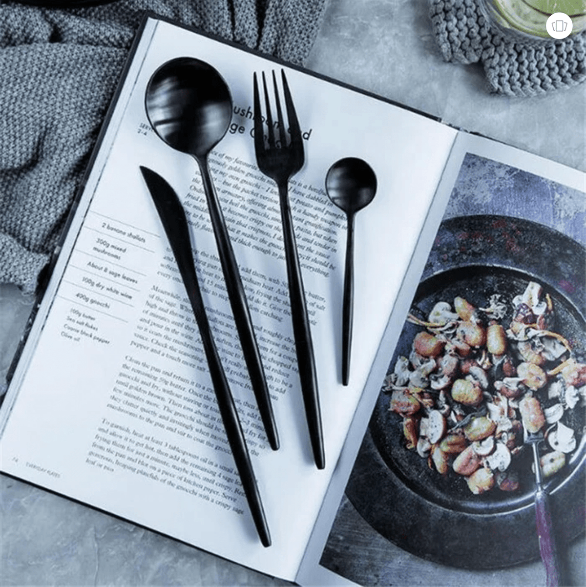Black cutlery set on an open magazine with food photography on the other page.