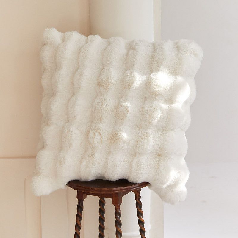 White textured throw blanket on a wooden stool against a neutral wall