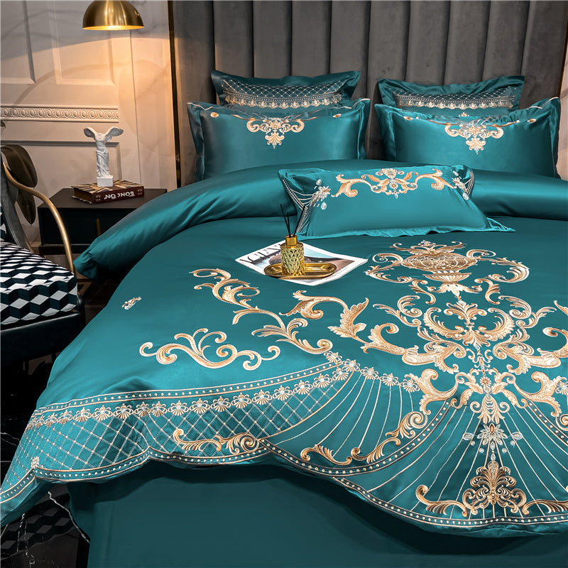 Teal bedspread with gold embroidery on a bed in a bedroom setting.
