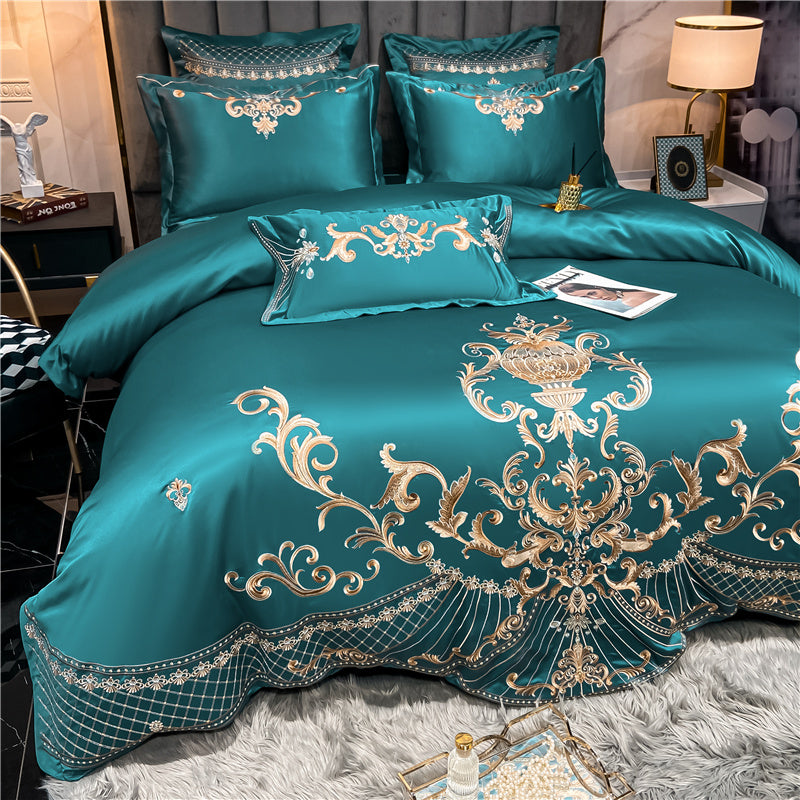 Teal bedspread with gold embroidery on a bed in a bedroom setting.