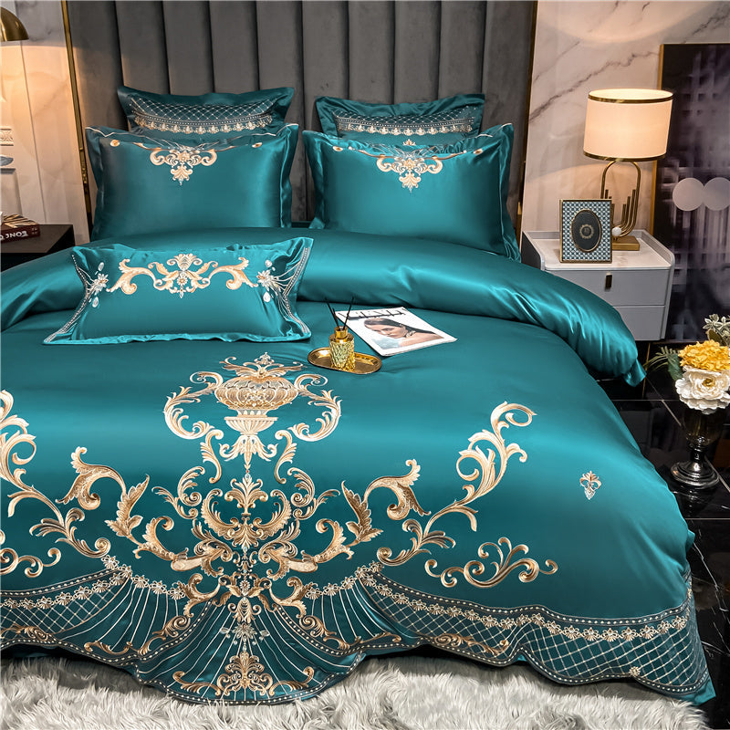Teal bedspread with gold embroidery on a bed in a bedroom setting.