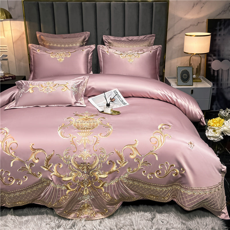 Luxurious pink and gold bedding set on a bed with decorative pillows and a nightstand.