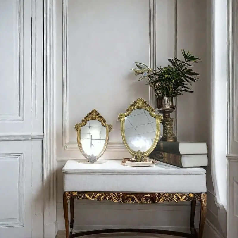 Decorative table with gold-framed mirrors and a plant in a stylish interior setting.