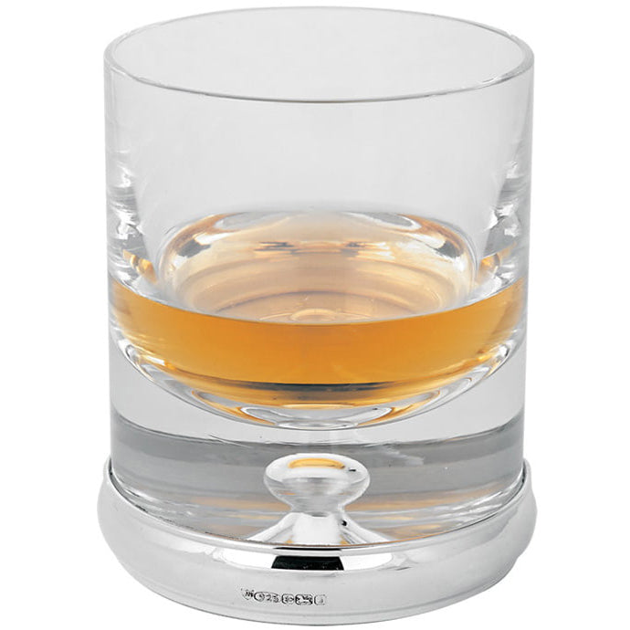 Clear glass with a sterling silver base containing a small amount of amber liquid on a white background