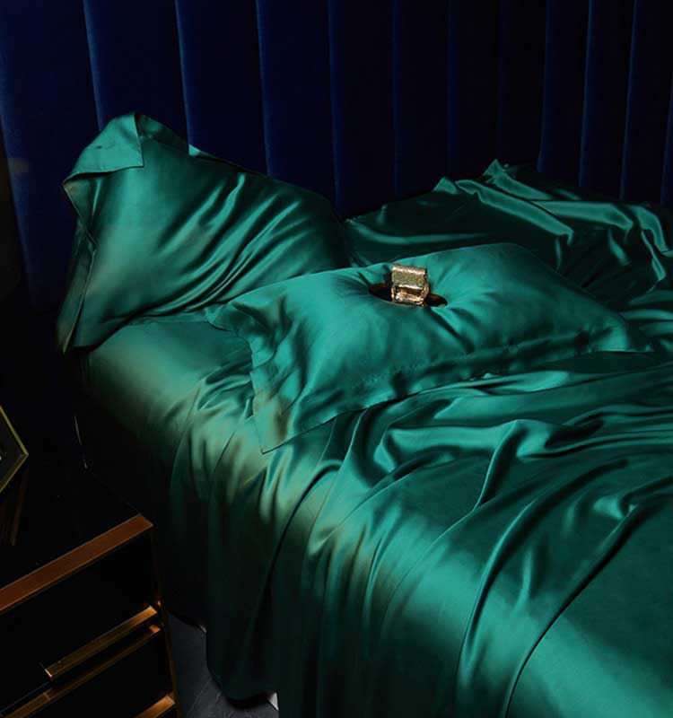 Teal bedding set on a bed with a dark blue headboard.