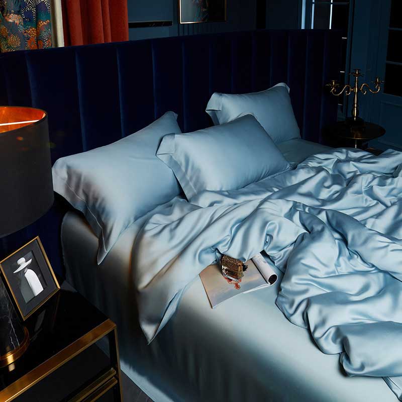 Bed with light blue bedding in a dimly lit bedroom