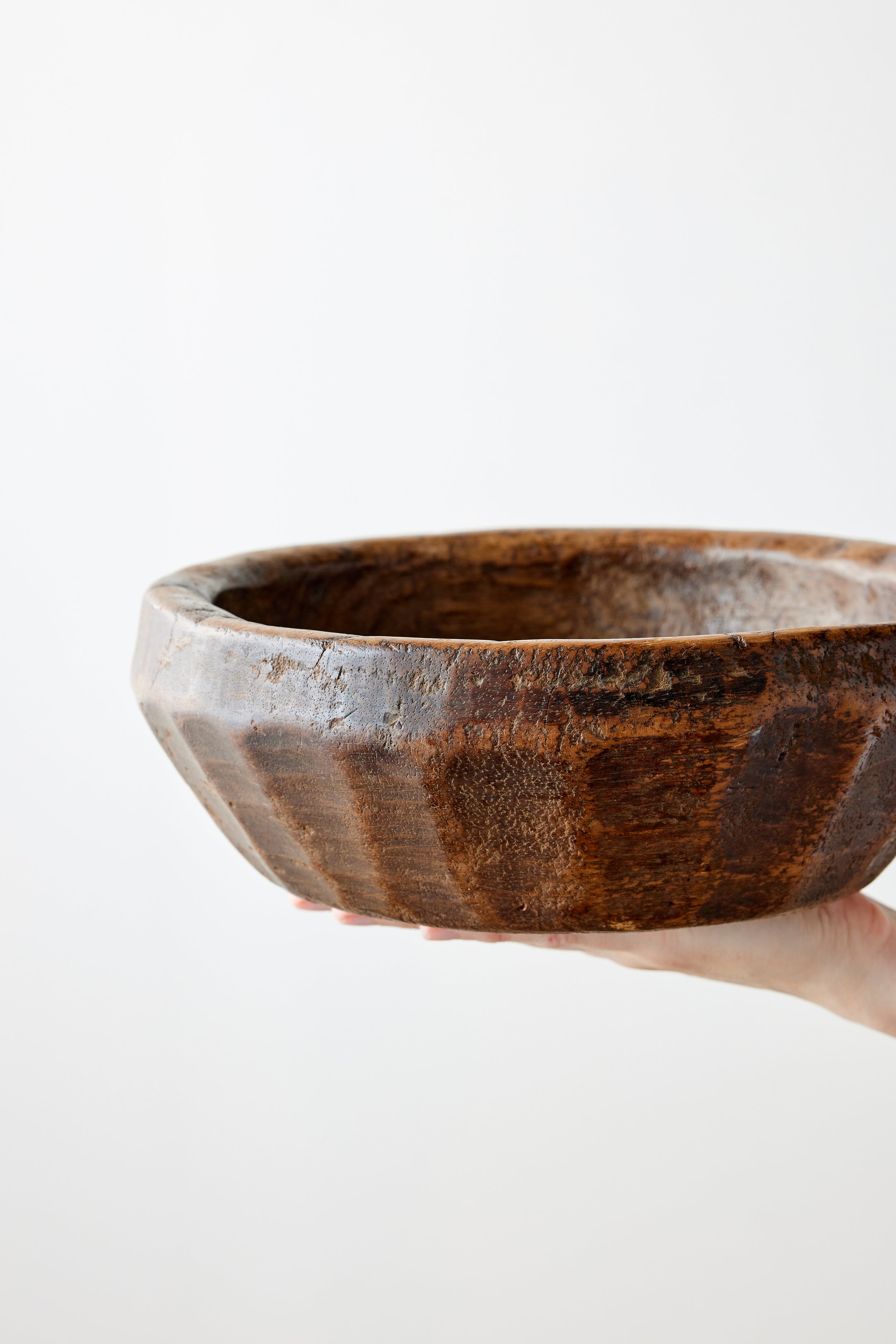 Hand holding a wooden bowl with a white background