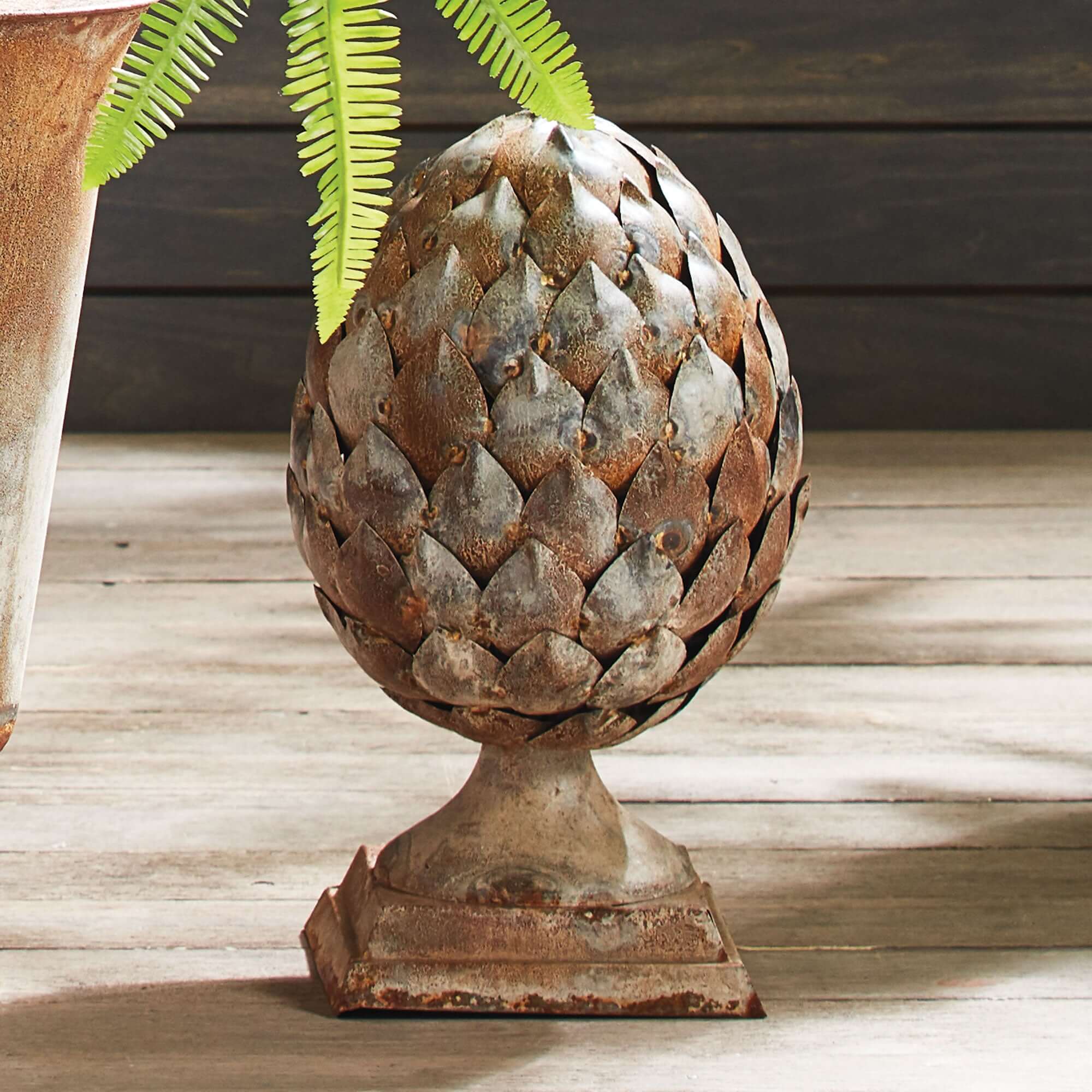 Decorative metal artichoke sculpture on a wooden surface with a rustic finish.