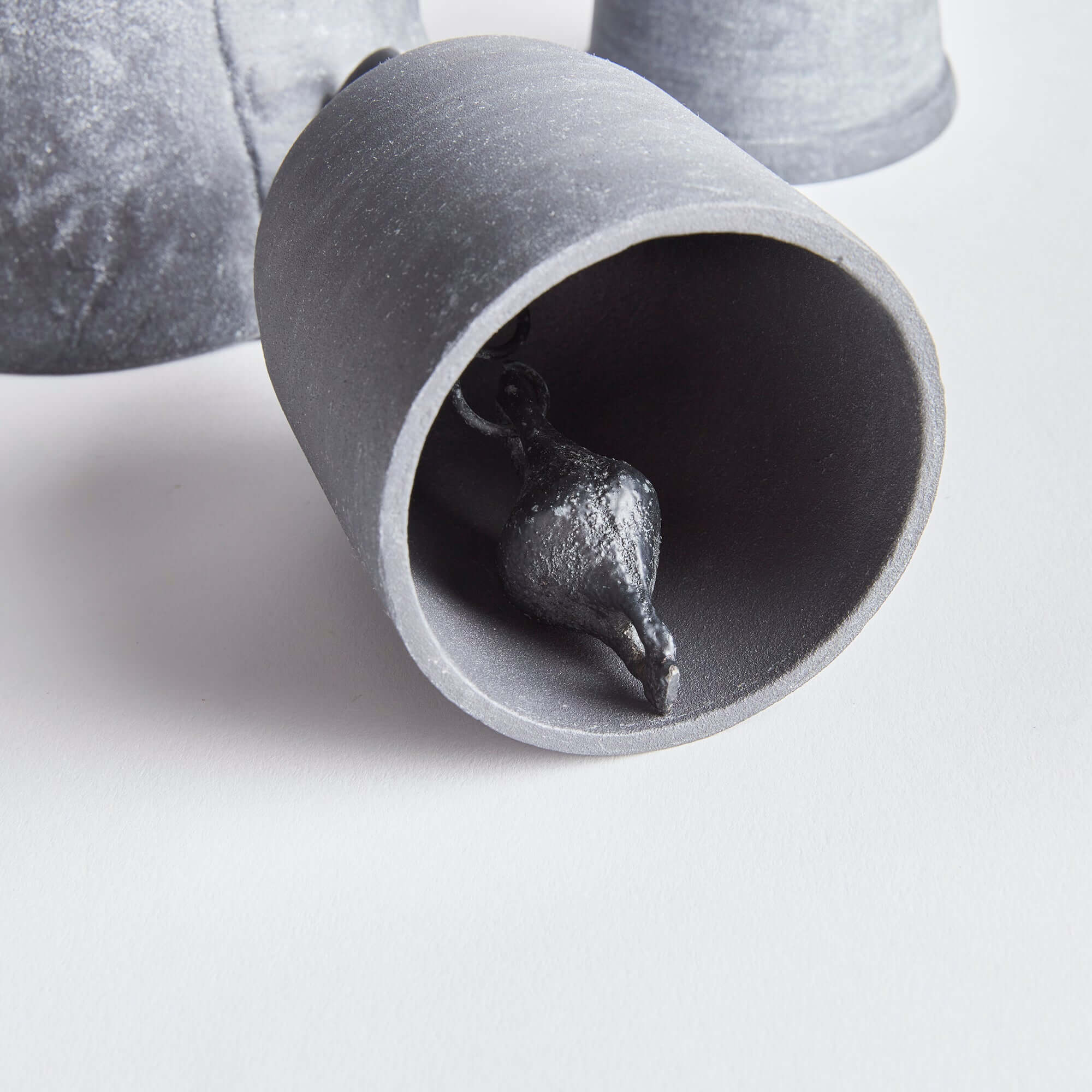 Metallic sculpture of a fish inside a cylindrical concrete-like tube on a light gray background