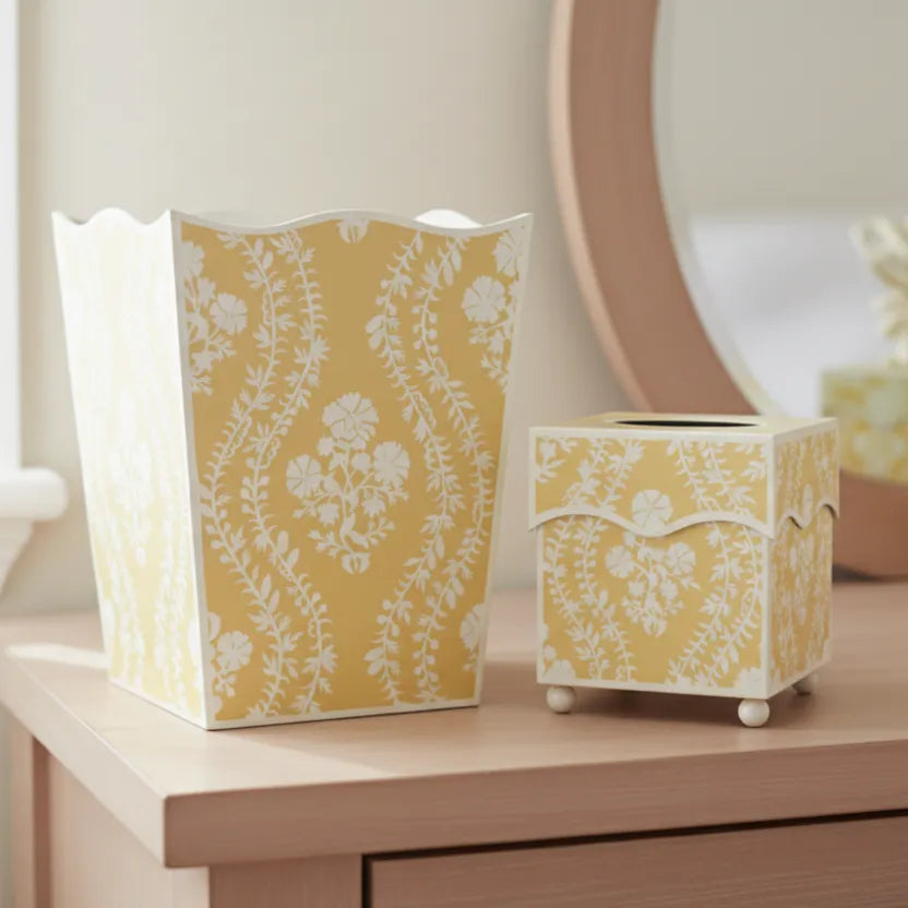 Butter yellow floral patterned wastepaper basket and tissue holder on a bedroom dresser with a mirror in the background