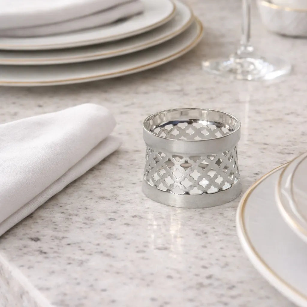 Silver plated napkin ring on a marble countertop with napkin and dinnerware