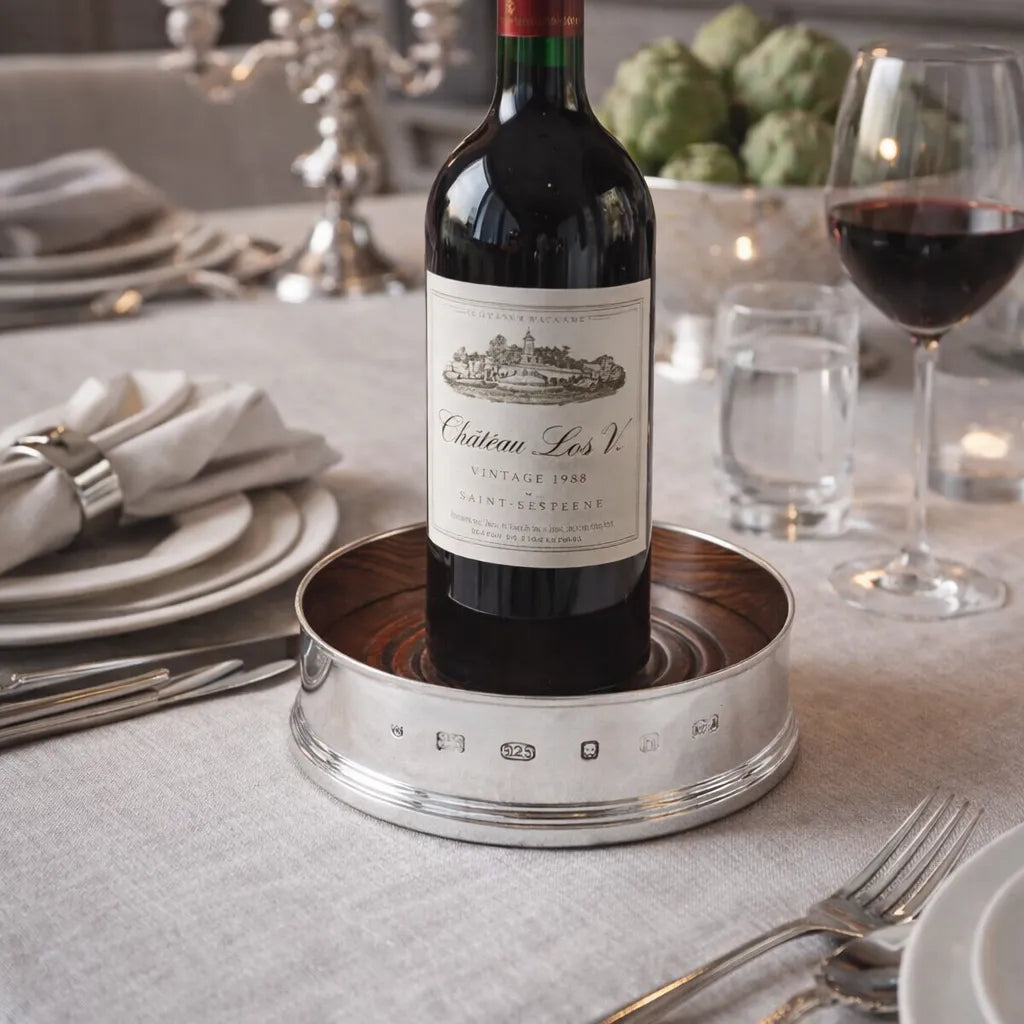 Wine bottle on a sterling silver coaster with a dinner setting in the background
