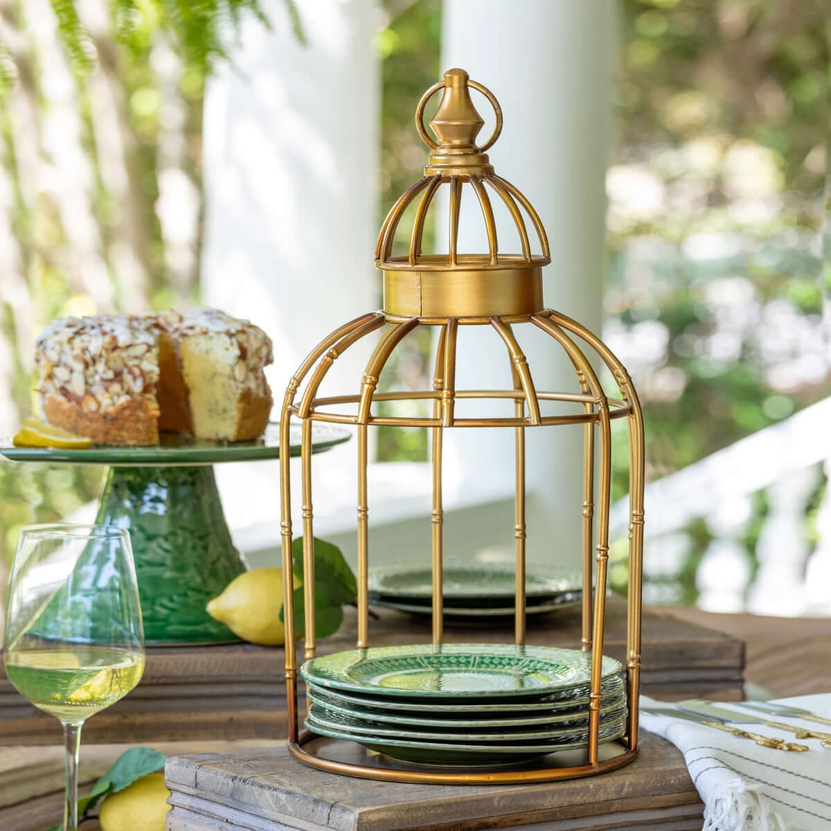 Gold bird cage with green plates on a table outdoors