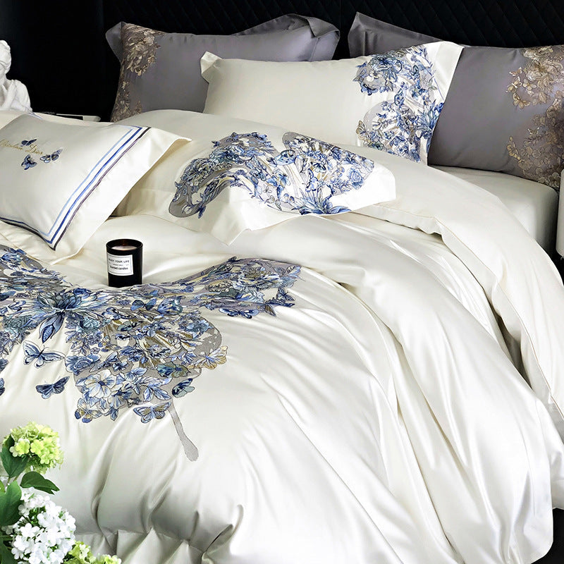Delicate floral and butterfly patterned bedding set on a bed with a candle and flowers.
