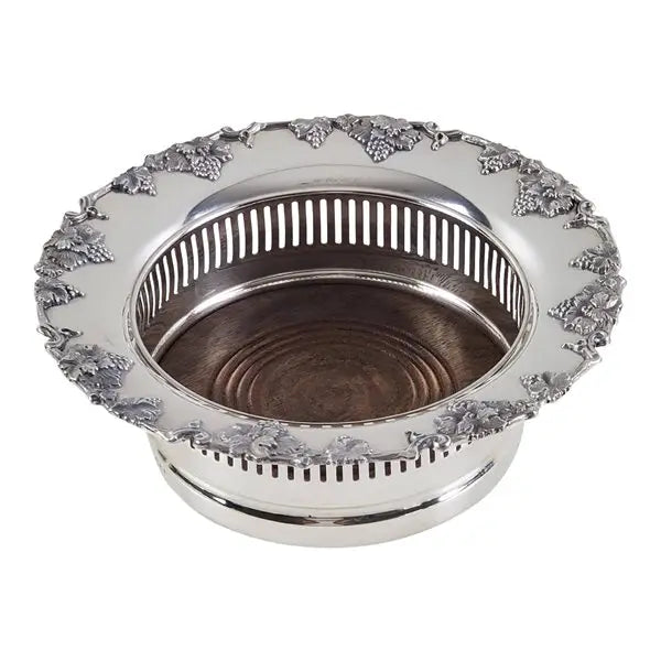 English silver plate wine coaster with grape border and wood base, designed to hold a standard wine bottle on white background