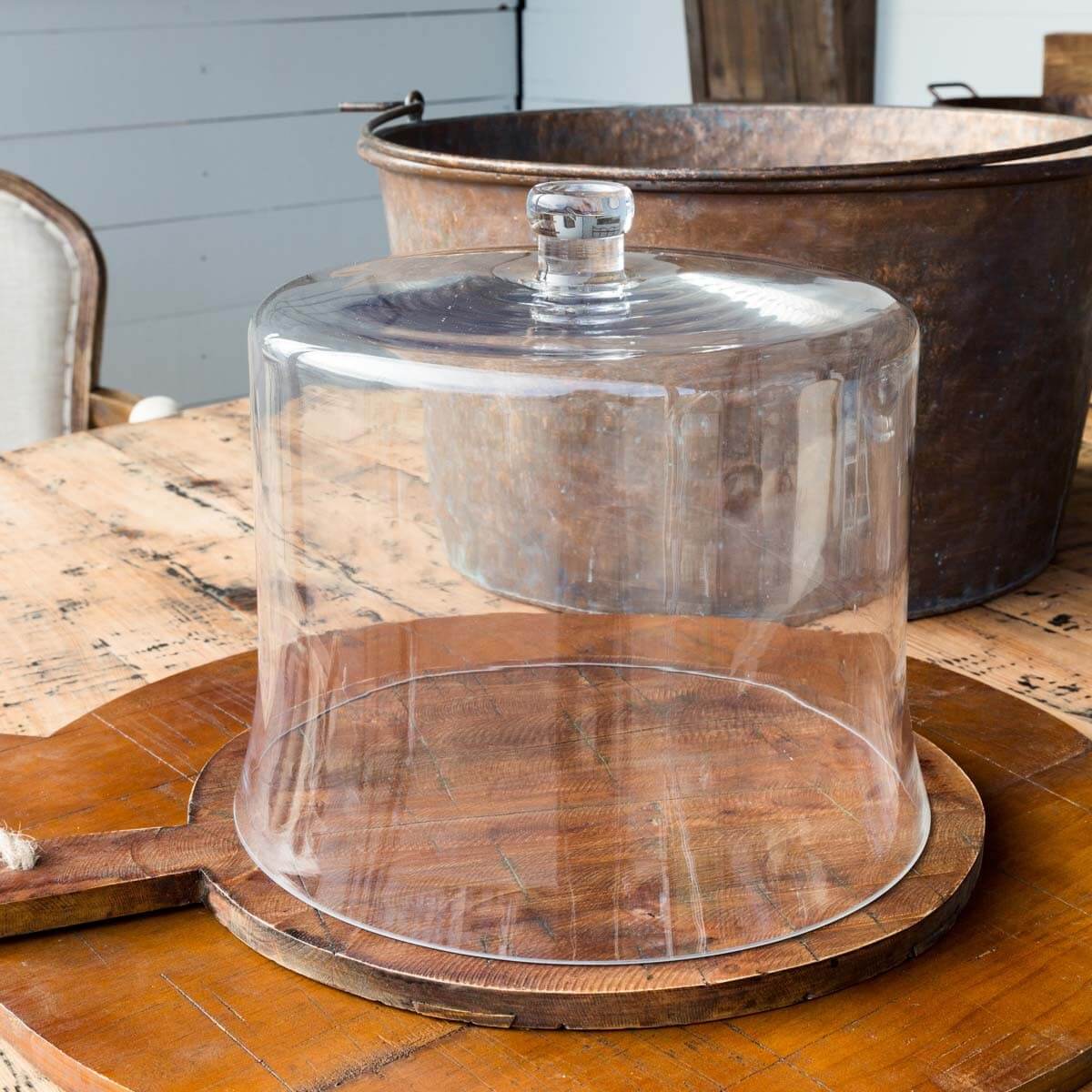 Clear glass dome cloche on a wooden stand with a rustic background