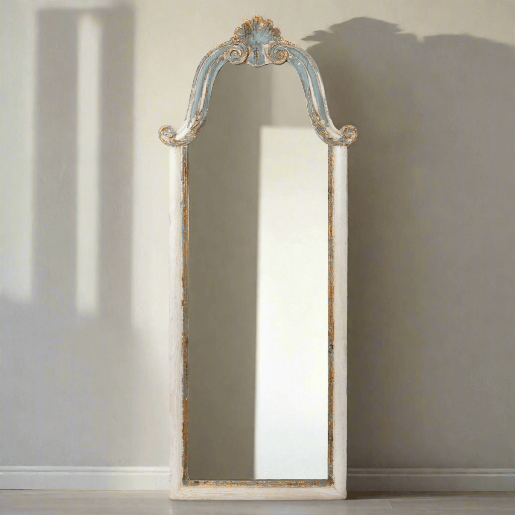 Decorative floor mirror with ornate frame on a neutral background