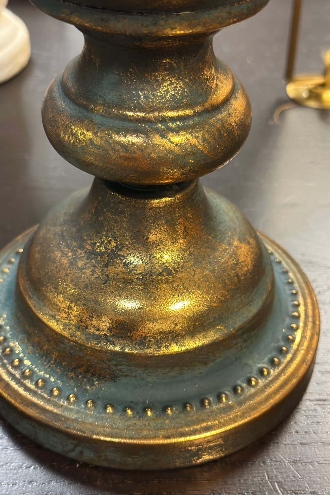 Close up of the base of a gold urn vase with patina finish
