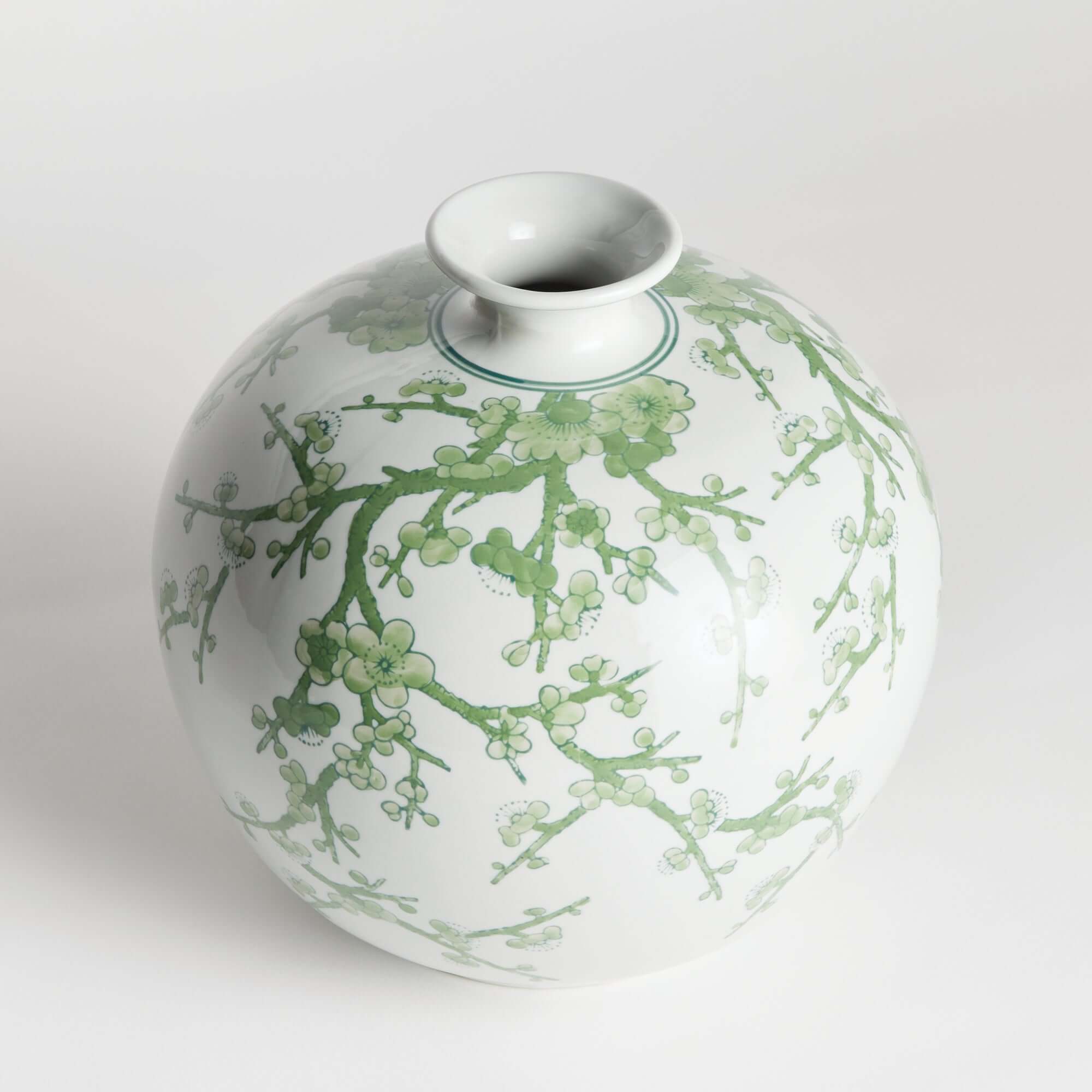 Ceramic vase with green floral patterns on a white background