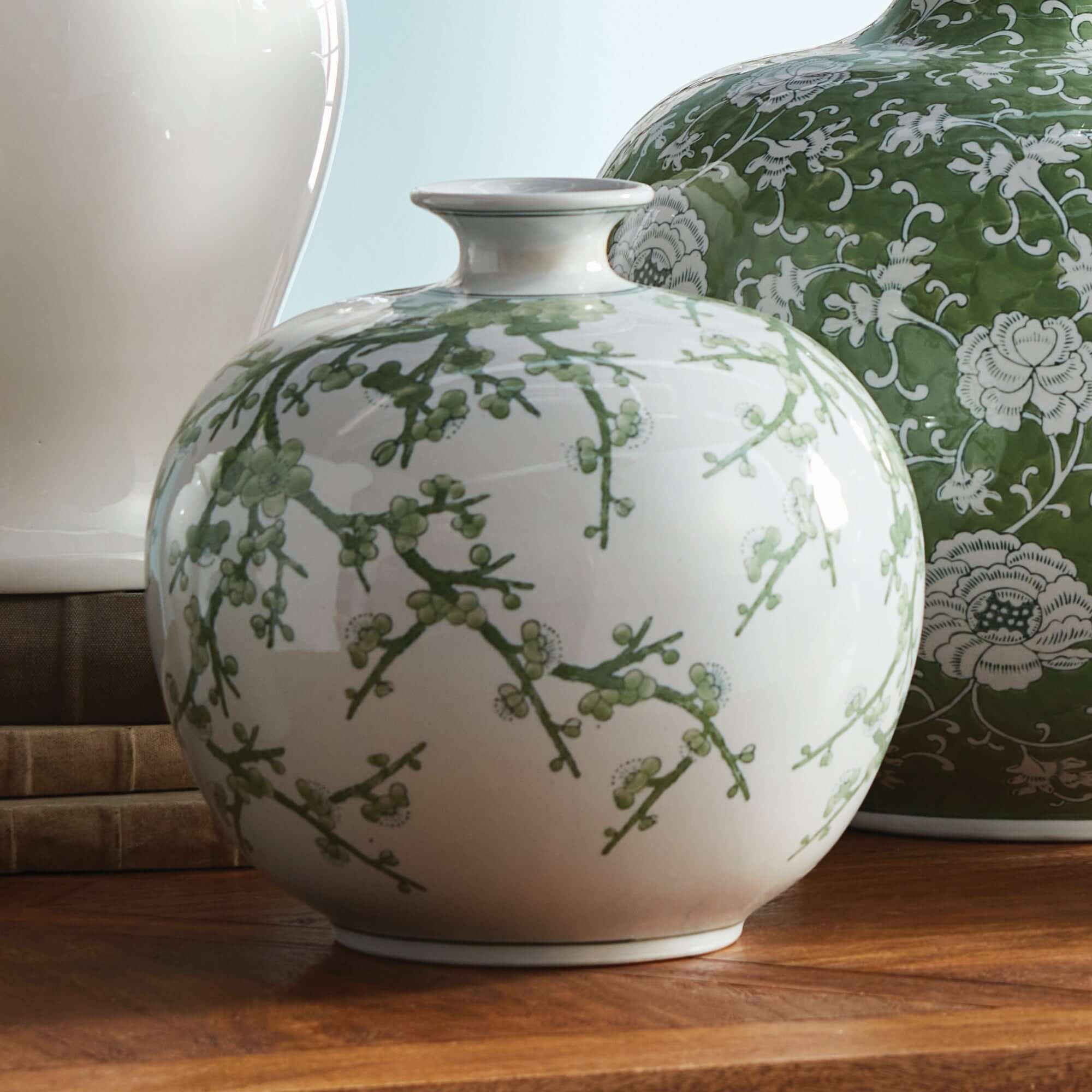 White vase with green floral patterns on a wooden surface