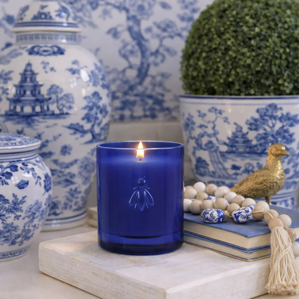 La Rochere Winter Garden blue candle in a decorative chinoiserie setting with blue and white jars and a plant.