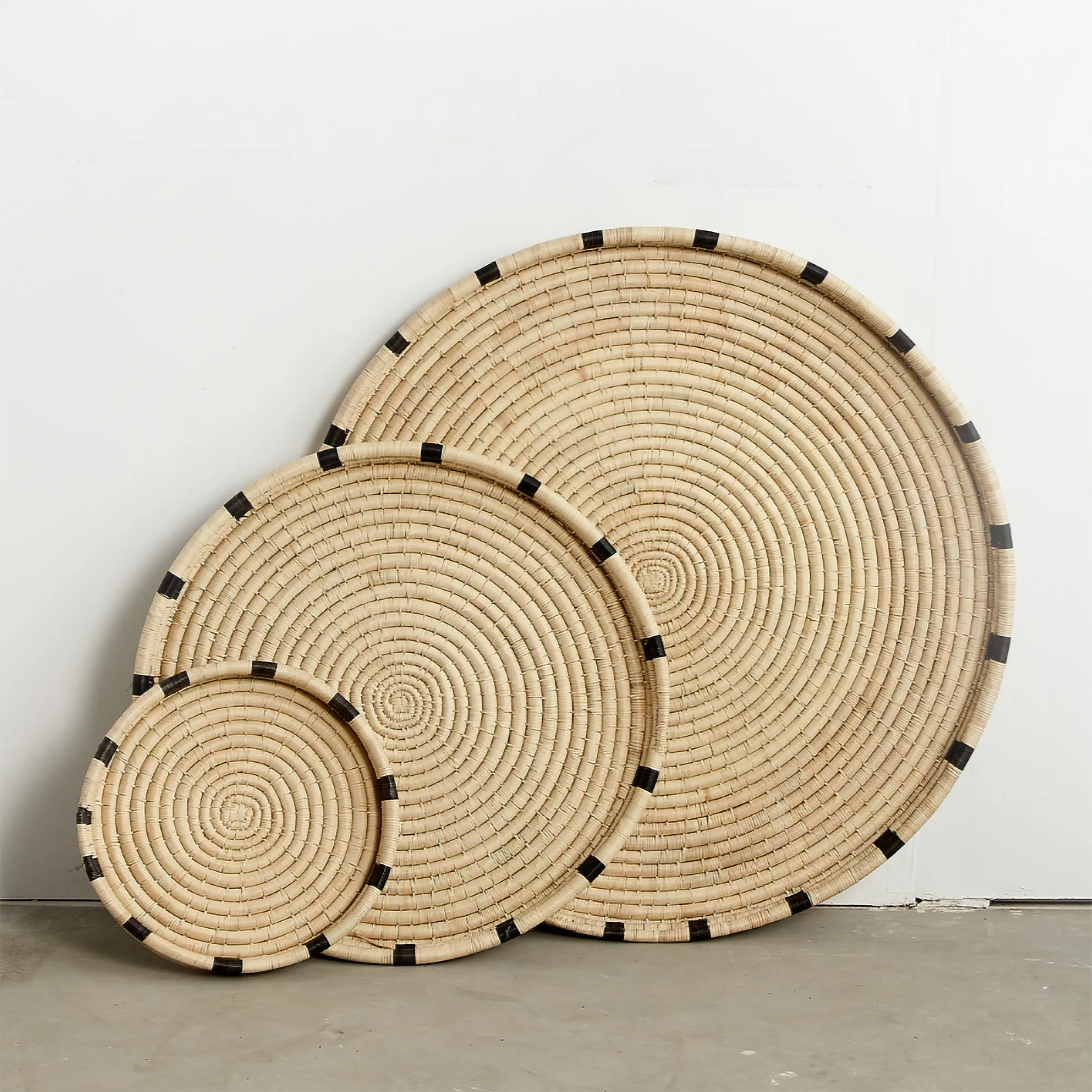 Set of hand woven trays with black accents on a plain background