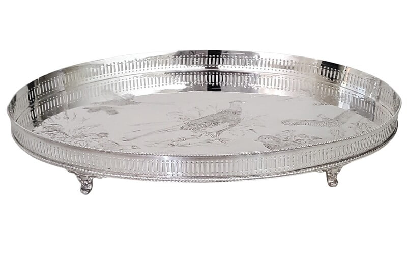 Silver decorative tray with intricate designs on a white background