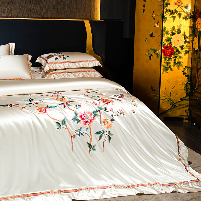 Bed with floral embroidery in a room with a decorative screen.