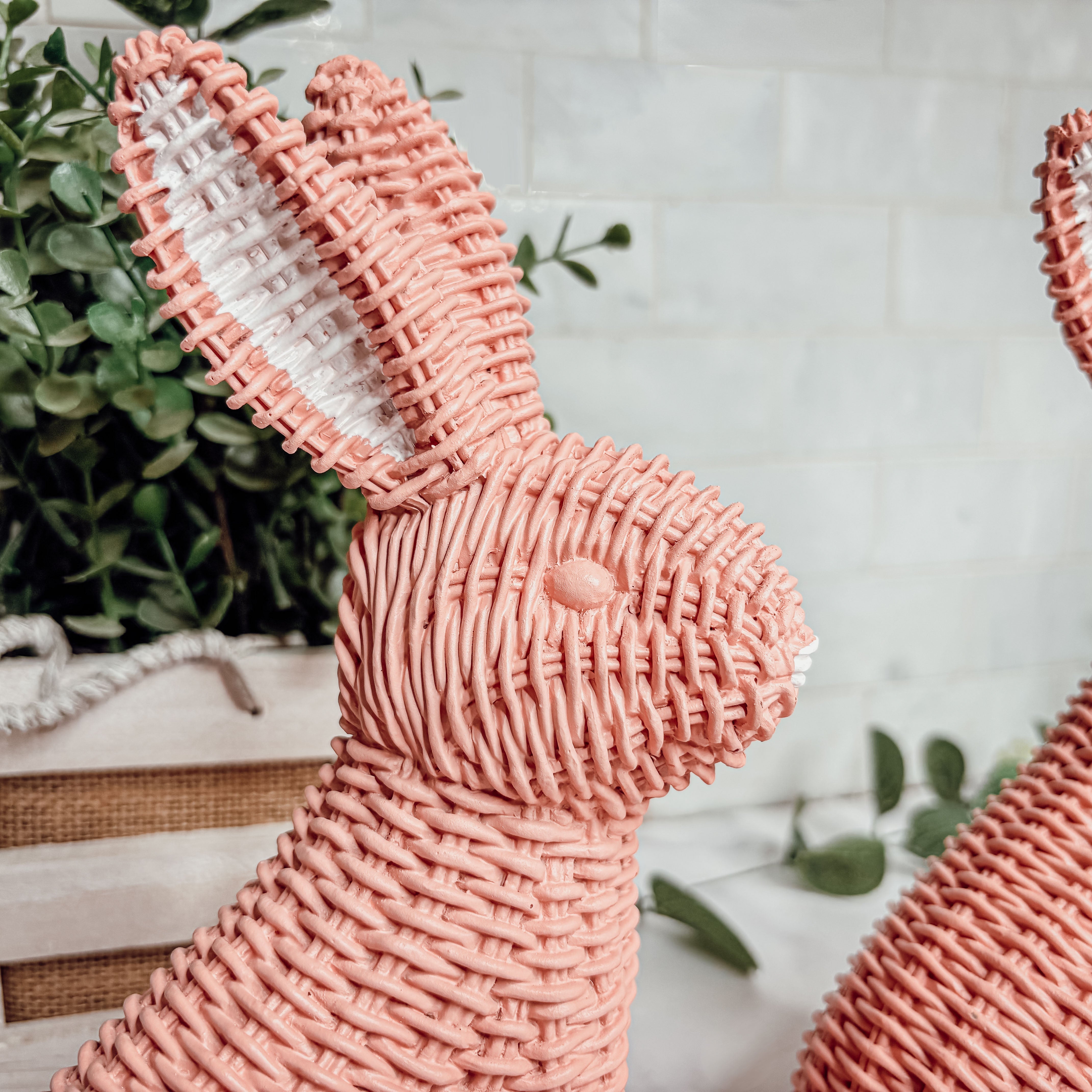 Pink woven bunny figurine with a white interior on a light background