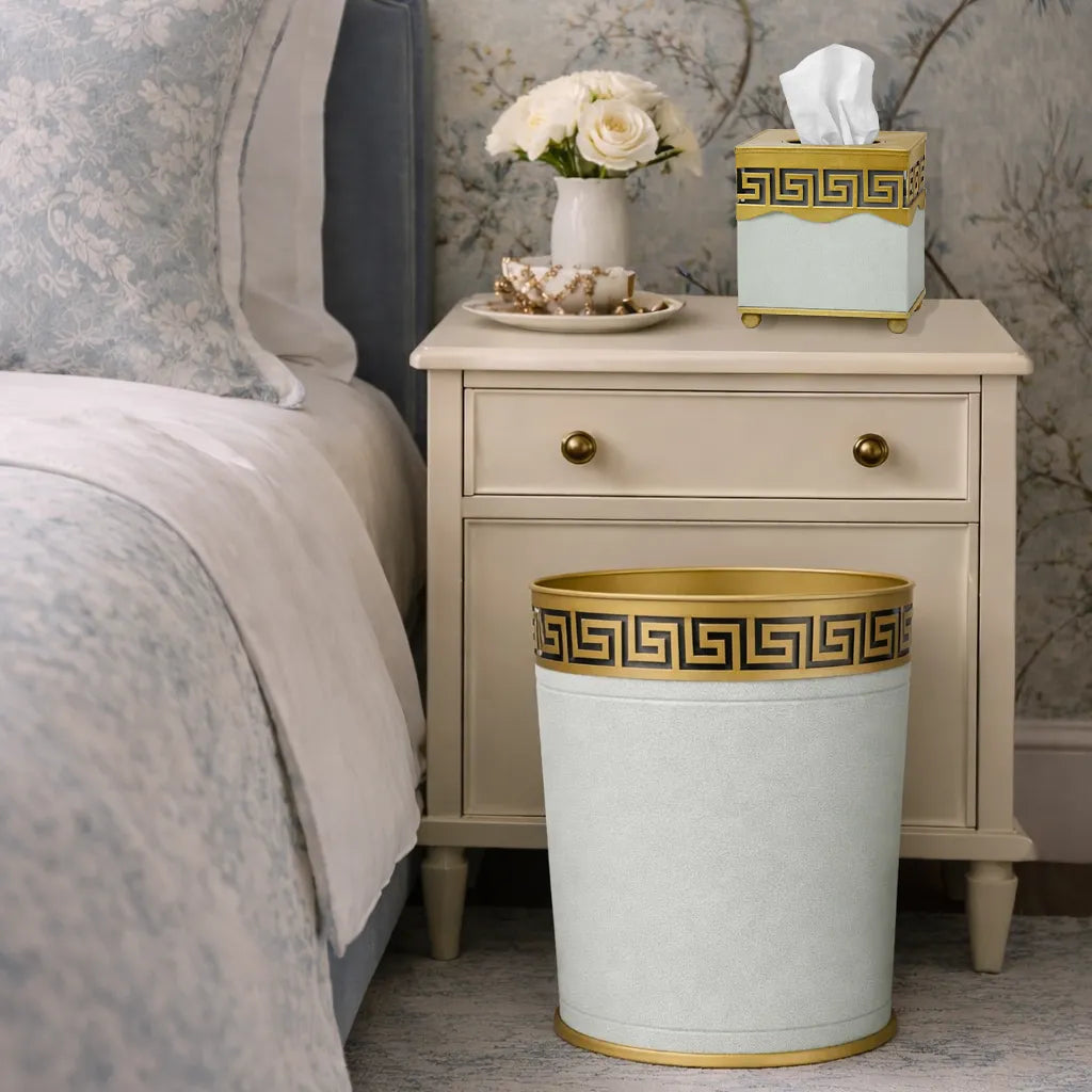 Soft green greek key bathroom wastepaper basket and tissue holder near a nightstand in a bedroom setting.