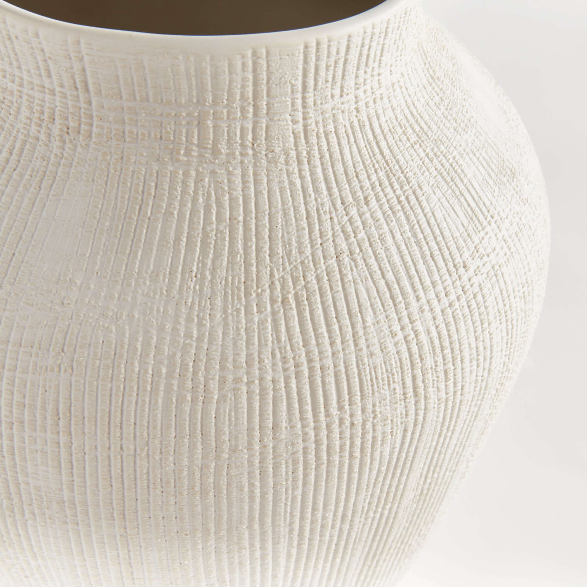 Close-up of a textured white ceramic vase on a light background